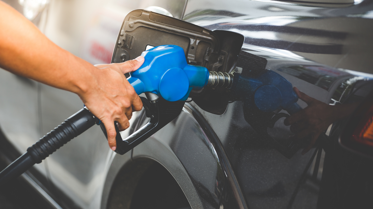 Hand refilling car with fuel at a gas station.