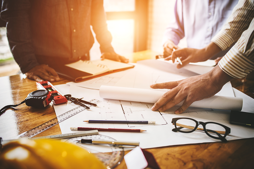 Consultation between colleagues, engineering team to check the blueprint used to build commercial buildings for joint ventures. Engineering team meeting to analyze the blueprints of a commercial building using various measurement tools and software.